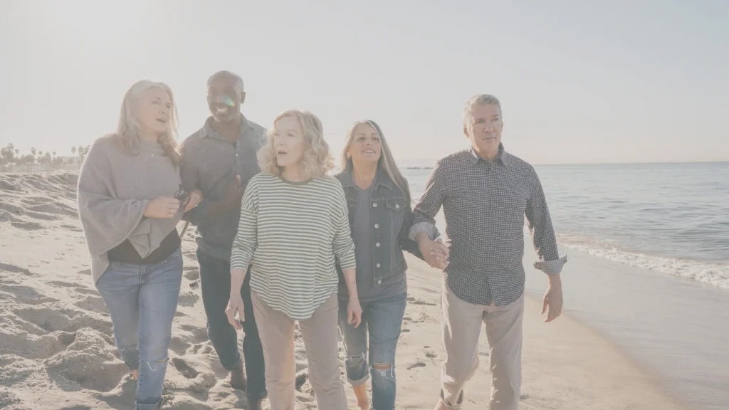 Group of seniors walking along the beach – enjoying retirement with peace of mind from life insurance.