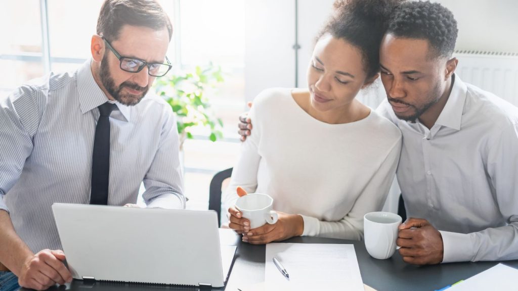 Canadian couple comparing life insurance quotes on a laptop at home with an agent 