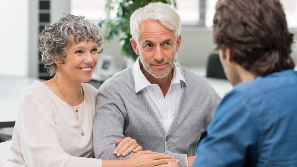 Retired Canadian couple talking to an advisor representing the long-term peace of mind provided by permanent life insurance coverage.
