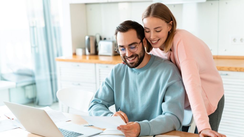 Young Canadian couple reviewing term life insurance options at home with laptop